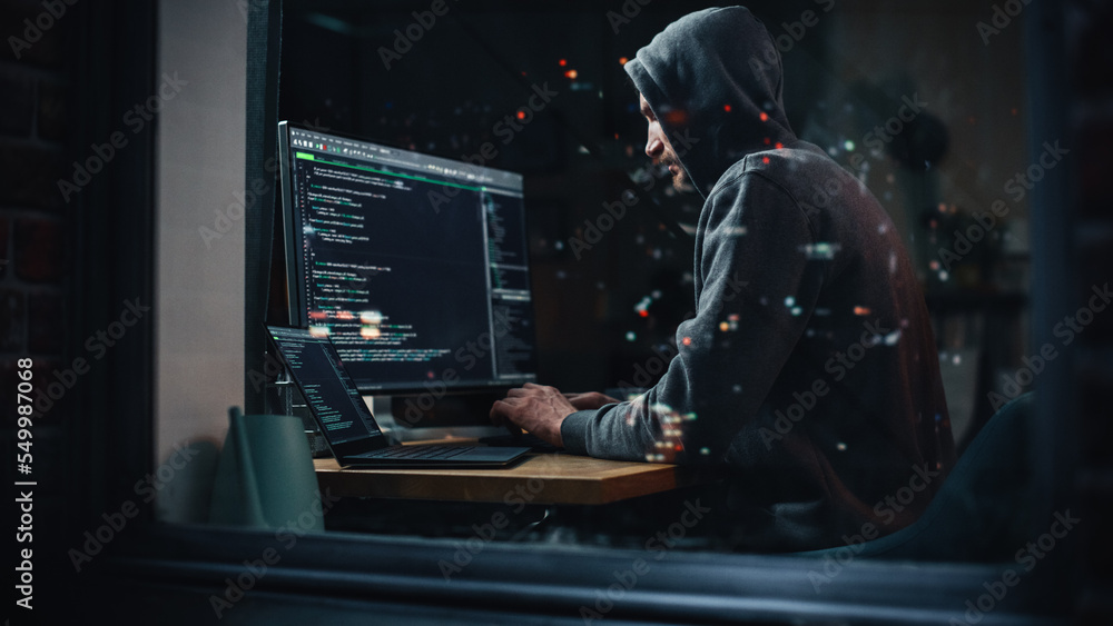 Fototapete Hacker Using Desktop Computer to Perpetuate Cyber Attack, Doing DDOS Attack, Sends Viruses, Phishing Software, Malware, Stealing Private Data, Credit Card Fraud. Shot into City Apartment Window.