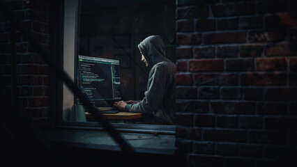 Night Apartment: Evil Male Hacker wearing Hoodie Breaks into Data Server Room, DDOS Attack, Phishing Scheme, Malware. Darknet Cyber Crime Concept. View From Outdoors into Window. - obrazy, fototapety, plakaty