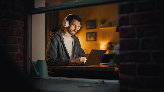 Professional Software Engineer Working From Home Office. Tired IT Specialist Feeling Sleepy and Finising Important Project. Application Development Process. View From Outdoors into Window.