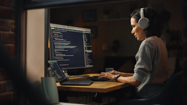 Brazilian Female Programmer Working On Computer At Home. Brilliant Female IT Programer Using Desktop Computer Late Night. Professional Developer Programming Code. Shot Into The Window From Outside.