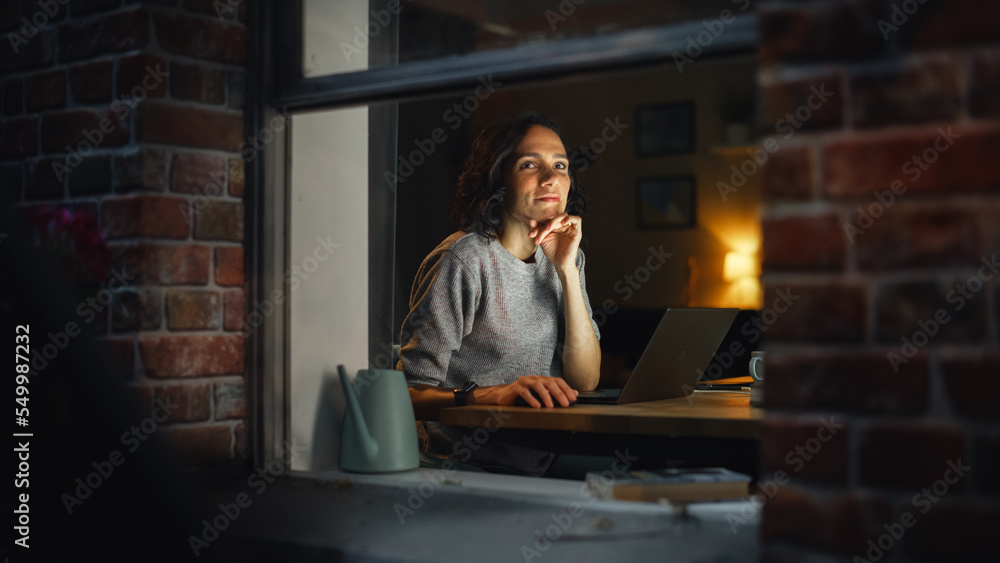 Aufkleber smiling hispanic woman at home using laptop on the warm cozy evening and looking thoughtfully. profe