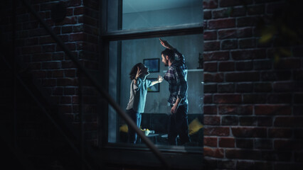 Couple Arguing and Fighting Horribly. Domestic Violence and Emotional abuse Scene, Stressed Woman and Aggressive Man Screaming at Each other in Dark Apartment. Dramatic Scene. Shot from Outdoors.