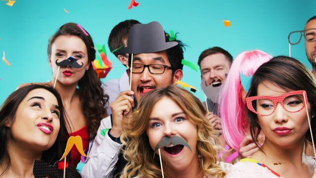 Friends party, confetti and dancing with happy smile and portrait and celebration for new year or birthday event together in studio background. Men, women or crazy people with mask in photobooth
