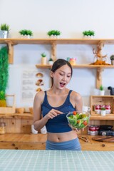 Young beautiful asian female adult lady in gym outfit after yoga exercise. Eat clean food salad with tomato for healthy and slim fit lifestyle.
