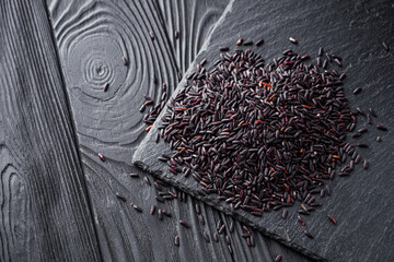 raw fresh black rice on black wooden rustic background