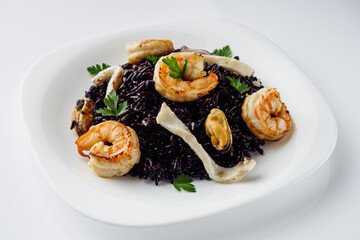 delicious black rice with shrimps and seafood on a white background
