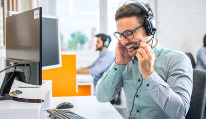 Happy handsome technical support operator with headset working in call center.
