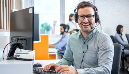 Young male technical support dispatcher in call center. Man in call center with headset helping...
