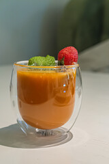 Orange buckthorn drink in a transparent cup decorated with strawberries