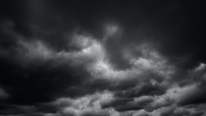 dark dramatic sky with black stormy clouds before rain or snow as abstract background, extreme weather, the sun shines through the clouds, high contrast photo