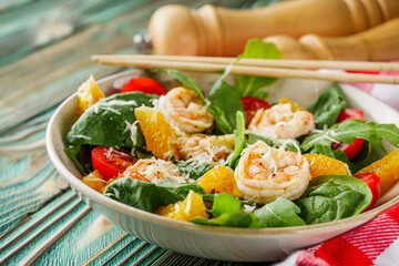 delicious fresh shrimp salad with orange and cherry tomatoes on a wooden rustic background