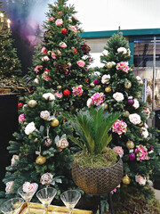 Christmas tree decorated with trendy artificial flowers, garlands and Christmas baubles