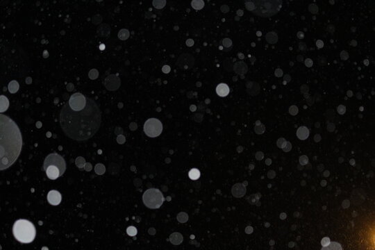Abstract winter snowflakes idea bokeh effect on black background, Snow falling concept with glowing light at bottom right. Abstract christmas winter background
