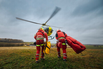 Two paramedic with safety harness and climbing equipment running to helicopter emergency medical service. Themes rescue, help and hope. .. - 549995447