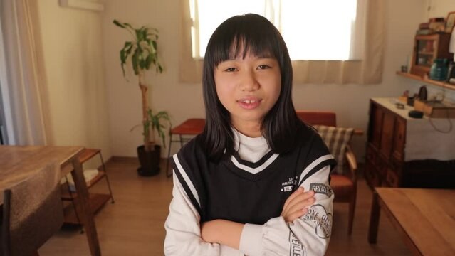 Asian teenage girl pretends to get mad but fails. Dolly in.