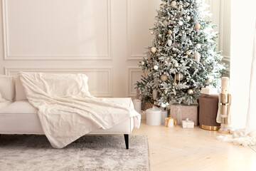 Comfortable couch with three cushions and a blanket standing in bright room interior with grey carpet in a modern interior. Modern interior living room with large light corner sofa and Xmas tree.	