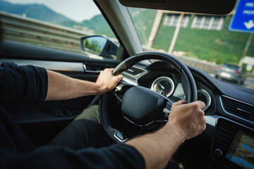 Male hands on a car's steering wheel