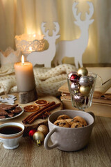 Cup of tea or coffee, various sweets and spices, Christmas decorations, comfy blanket, books and glasses. Selective focus.