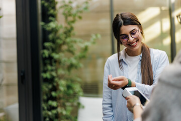Positive girl using her smart watch, paying over the payment machine.