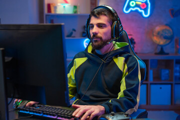 Naklejka premium Male gamer focusing on online video games championship, playing action game on online live stream. Caucasian player having fun with virtual esport gameplay tournament on computer. High quality photo