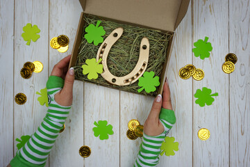 Women's hands hold a box with a gift for St. Patrick's Day 