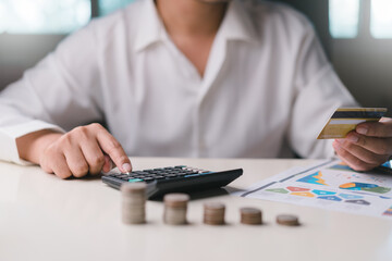 Businessman using calculator to calculate and holding a credit card, Stacking coins. Plan revenue and expenses, target success growth, finance profit management planning concept.