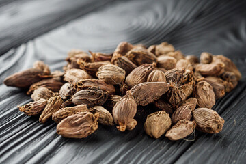 a barrel of dried black cardamom on a black wooden rustic background