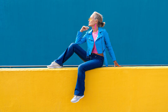 Thoughtful mature woman on yellow wall