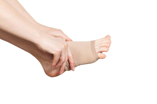 A woman puts on compression stockings for legs with varicose veins. Pain and swelling in the legs, phlebology. White background, close-up. Bloodstream