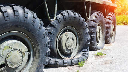 Flat and punctured wheels of armored personnel carriers during a military battle. Military conflict and weapons, sunset