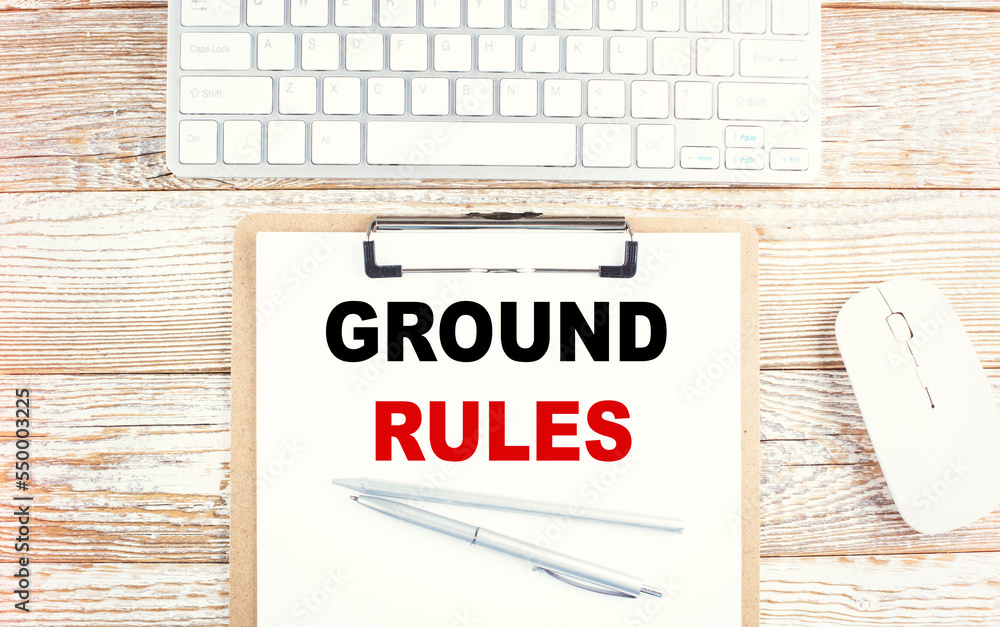 Aufkleber ground rules text on a clipboard with keyboard on wooden background
