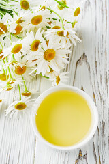 aromatic chamomile essential oil on a white wooden rustic background