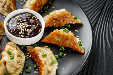 delicious fried gyoza dumplings on a black plate