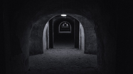 A long dark tunnel of a bomb shelter with a light at the end of the tunnel. Shelter of a bomb shelter in wartime Black and white photography