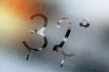 Inscription number 32 degrees Fahrenheit climate temperature on misted wet glass of window....