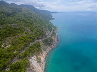 Aerial view of tropical winding road following blue ocean and rainforrest