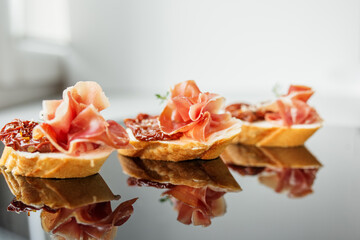 Appetizer with prosciutto, bruschetta and sun-dried tomato. Food, restaurant and event concept.