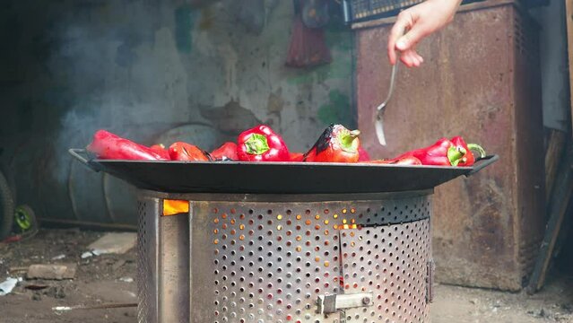 Roasting red peppers for a smoky flavor and quick peeling. Thermal processing of the pepper crop on a metal circle. Brazier container used to burn charcoal fuel for cooking, heating or cultural