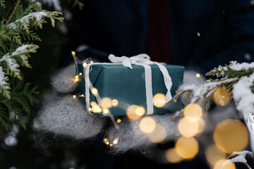 Hands in winter gloves with a handmade Christmas gift box