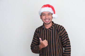 A man wearing Javanese costume and christmas hat smiling friendly