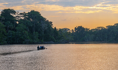 Canoe with tourists leaving at sunrise for an Amazon rainforest bird watching excursion, Yasuni...