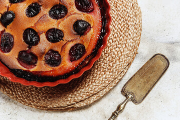 Fresh homemade plum pie in ceramic form on grey concrete background. Plum Skillet Cake. Delicious summer dessert. Selective focus - 550016852