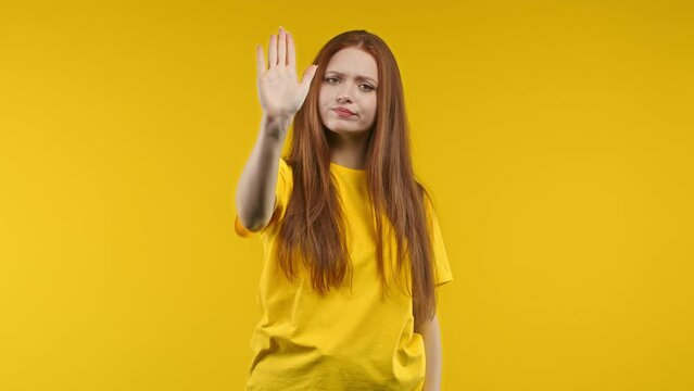 Uninterested woman disapproving with NO hand sign gesture. Denying, rejecting, disagree. Portrait of young lady on yellow background, timeout concept.
