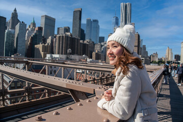 Young Asian tourist standing in Brooklyn bridge, tourist destination, standing view of the city at...