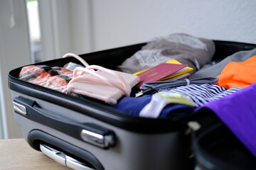 close-up of bright women's things, phone, folded clothes in open silvery suitcase, collecting...