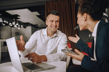 Man pointing at laptop looking at woman gesturing