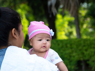 Portrait of happy Asia mother holding his newborn sweet baby dressed. The mommy embracing her baby with love and care. her daughter always happy when she is held.