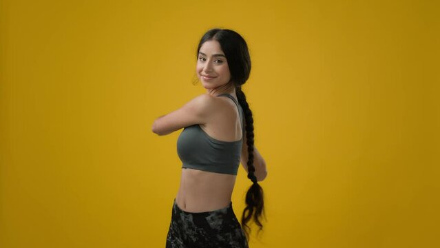 Strong slim sexy Indian ethnic woman sporty girl sports lady sport female athlete model in yellow studio background workout exercise stretching hands head bending neck body care yoga fitness stretch