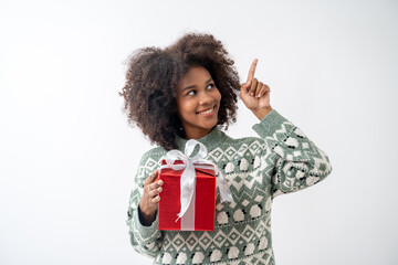Portrait of young attractive african american woman with curly hair presenting gift box in studio on white background.