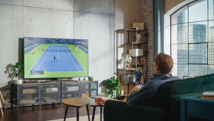 Sports Fan Watches Important Tennis Game on TV at Home, Focused on Important Championship. Cheering for His Favourite Sportsperson. Successful Players Compete Against Eachother in Tournament.